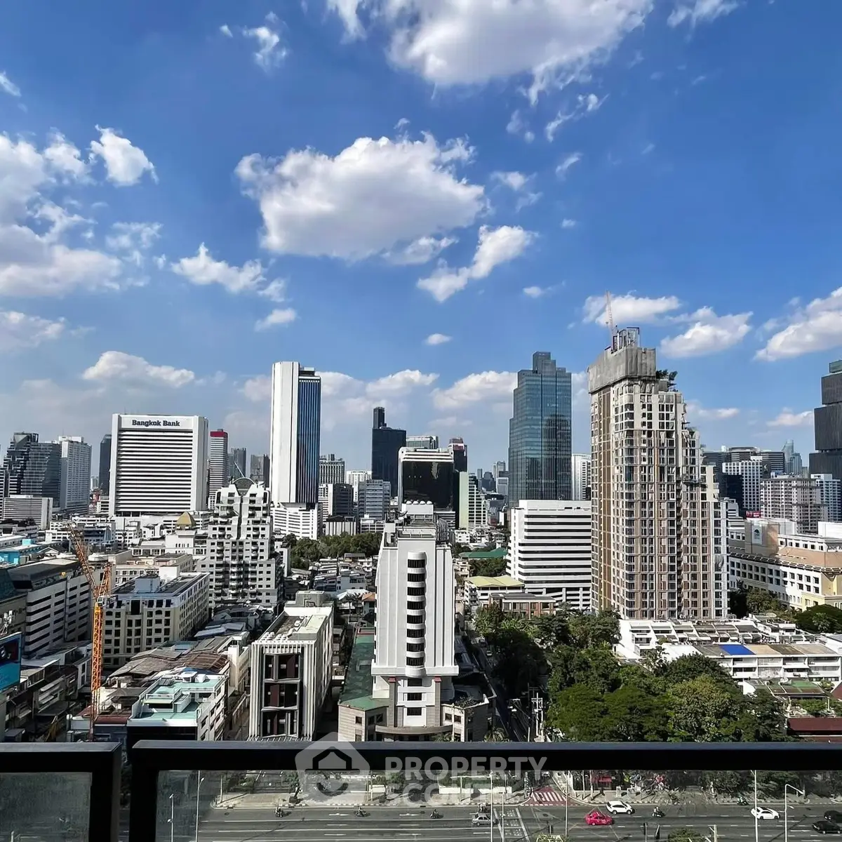 Stunning cityscape view from a high-rise balcony showcasing urban skyline and blue skies.