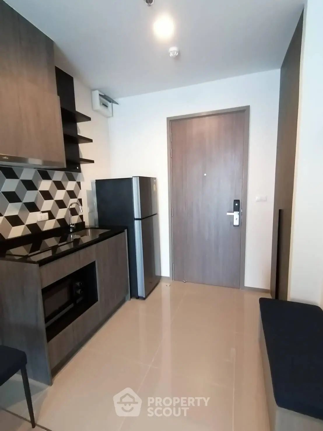 Modern kitchen with sleek design and closed layout, featuring a fridge and stylish backsplash.