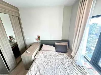 Cozy bedroom with city view, featuring a comfortable bed and modern wardrobe, perfect for urban living.