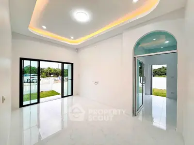 Spacious modern living room with large windows and elegant ceiling lights, offering a bright and airy atmosphere.