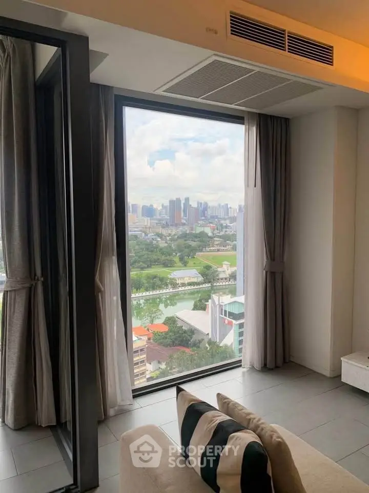Stunning city view from modern living room with large window and cozy seating.