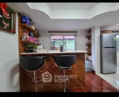 Stylish kitchen with modern bar stools and sleek refrigerator in a cozy home setting.