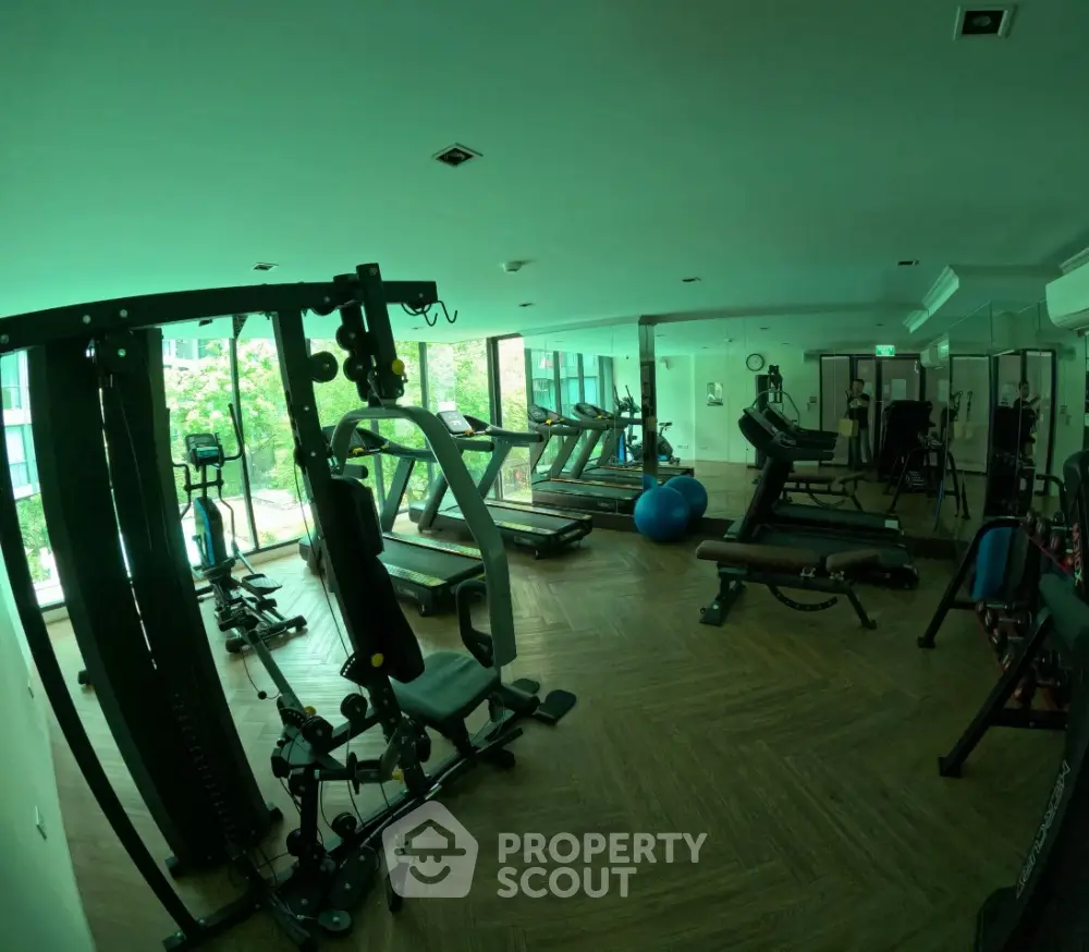 Spacious gym with modern equipment and large windows in luxury apartment complex