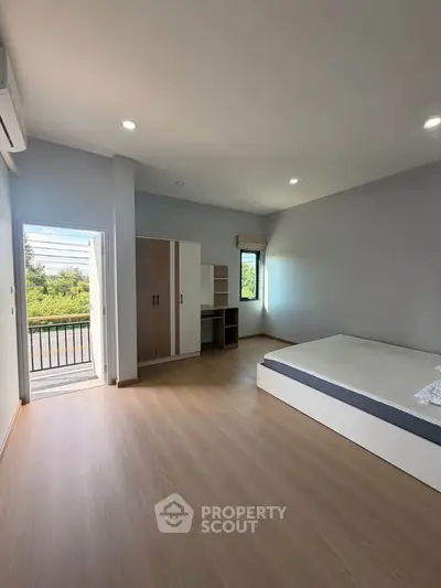 Spacious bedroom with balcony access and modern furnishings in a bright, airy apartment.