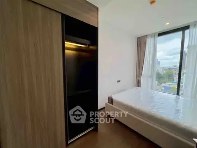 Modern bedroom with large window and city view, featuring sleek wardrobe and minimalist design.