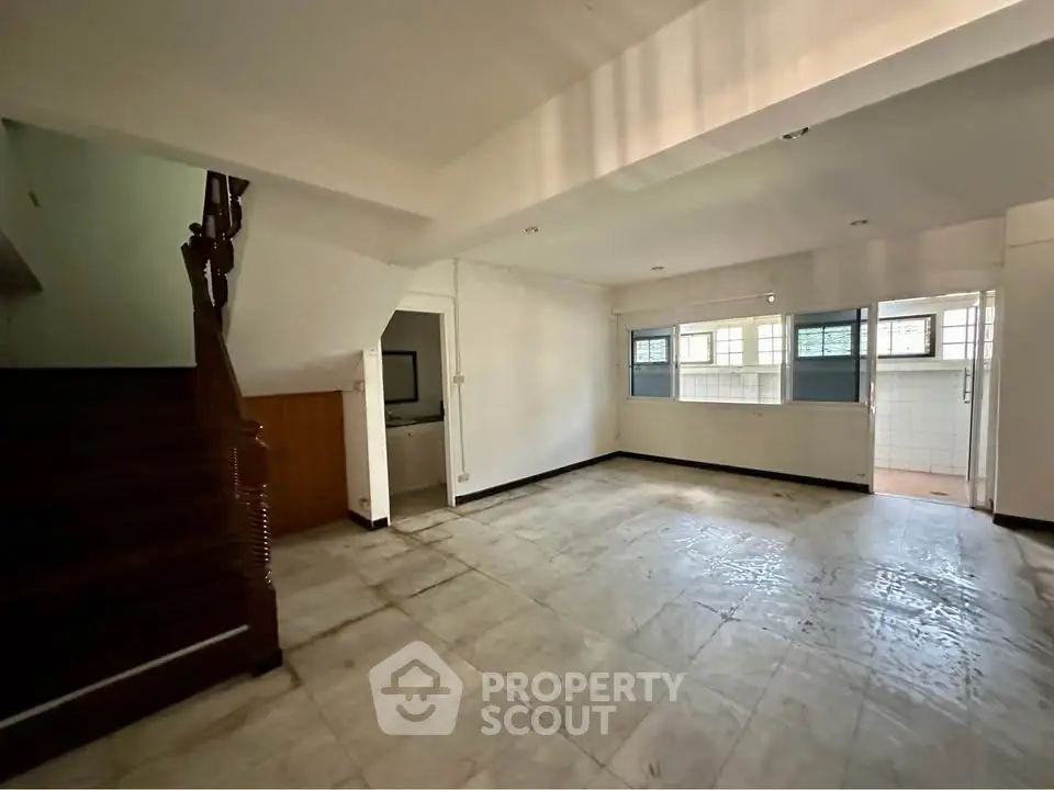 Spacious empty living room with staircase and large windows