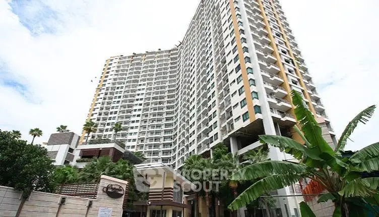 Modern high-rise apartment building with lush greenery and clear sky view.