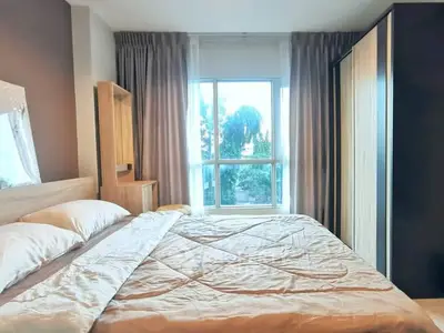 Cozy bedroom with large window and modern wardrobe, offering a serene view.