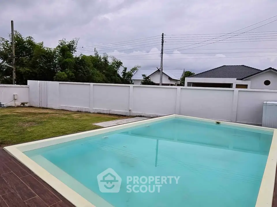Spacious backyard with a pristine swimming pool and lush greenery, perfect for relaxation and outdoor activities.
