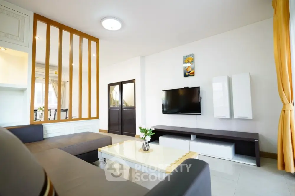 Modern living room with stylish decor and wall-mounted TV in a bright apartment.