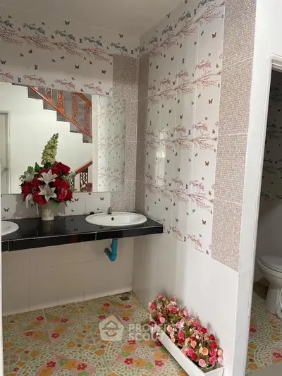 Charming bathroom with floral tiles and dual sinks, featuring elegant floral arrangements for a cozy ambiance.