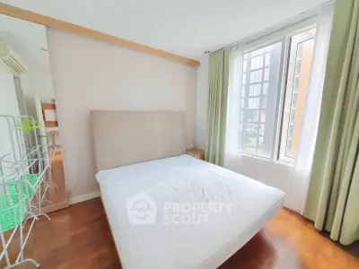 Bright and airy bedroom with large window and hardwood floors in modern apartment.