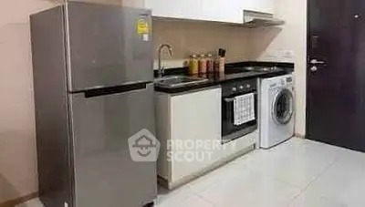 Modern kitchen with stainless steel fridge, oven, and washing machine in sleek apartment.