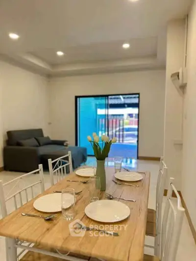 Modern dining area with elegant table setting and cozy living room in open layout apartment.