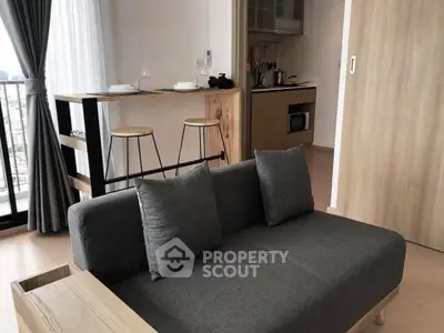 Modern living room with sleek gray sofa and stylish kitchen bar in open layout apartment.