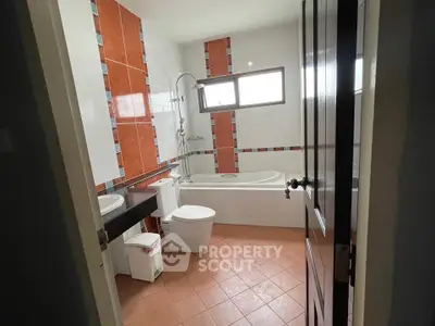Spacious bathroom with modern fixtures and bathtub in a bright, tiled setting.