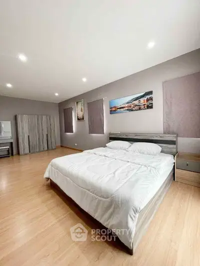 Spacious modern bedroom with wooden flooring and stylish decor