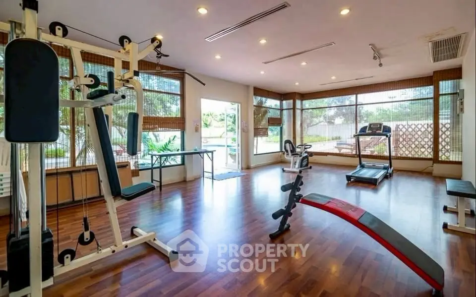 Spacious home gym with modern equipment and large windows offering garden views.