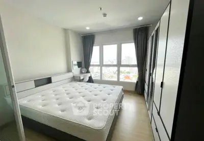 Spacious bedroom with large windows offering city views, featuring modern furniture and ample storage space.