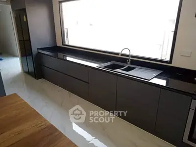 Sleek modern kitchen with black countertops and large window