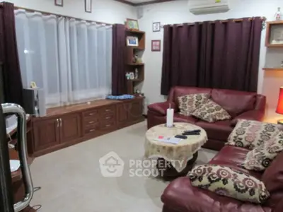 Cozy living room with leather sofas and elegant curtains, perfect for relaxation and entertainment.