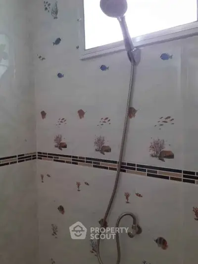 Charming bathroom with ocean-themed tiles and modern showerhead.