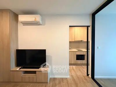 Modern living room with sleek TV setup and view into stylish kitchen