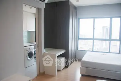Modern studio apartment with city view, featuring a compact kitchen and washing machine.