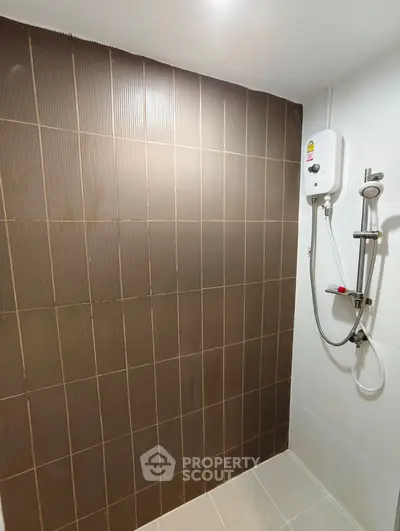 Modern bathroom with sleek brown tiles and wall-mounted shower heater.