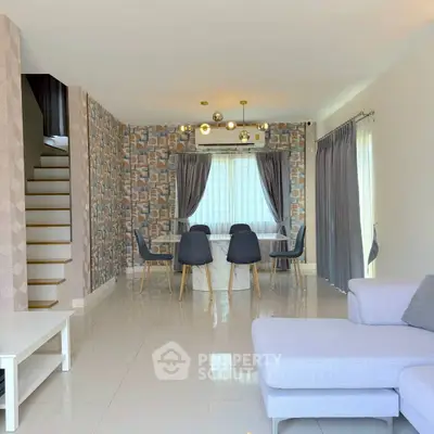 Modern living room with stylish decor and dining area, featuring elegant lighting and contemporary furniture.