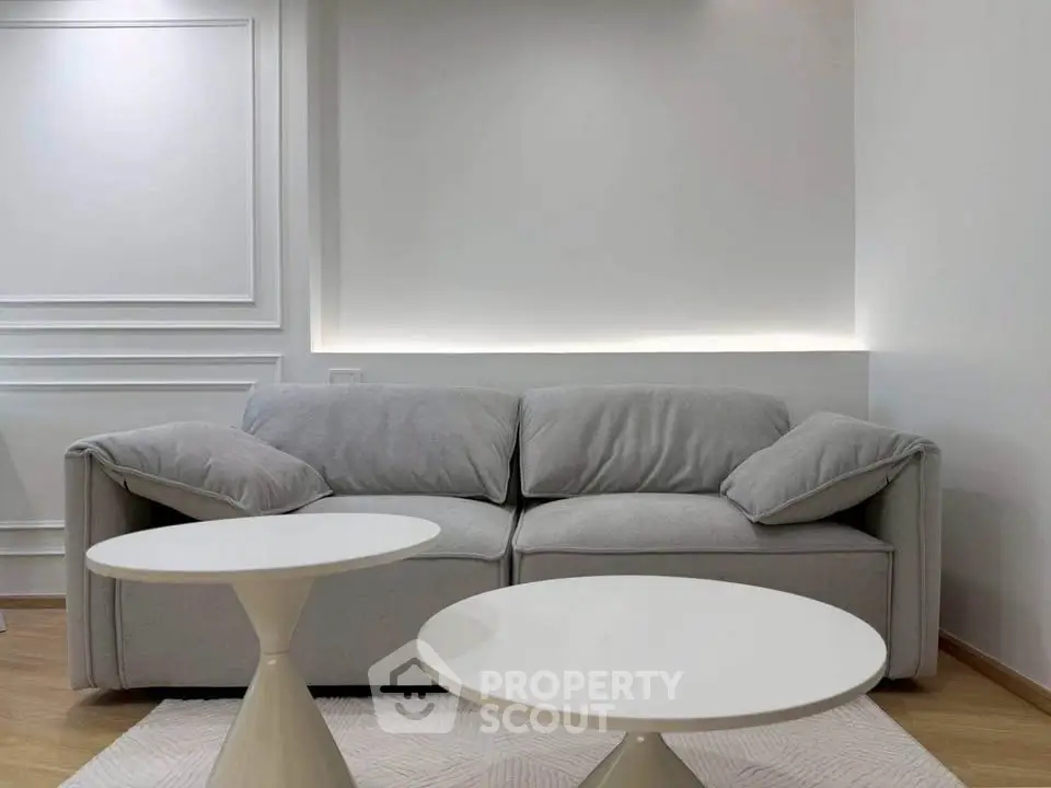 Modern living room with stylish gray sofa and chic white tables, perfect for contemporary urban living.