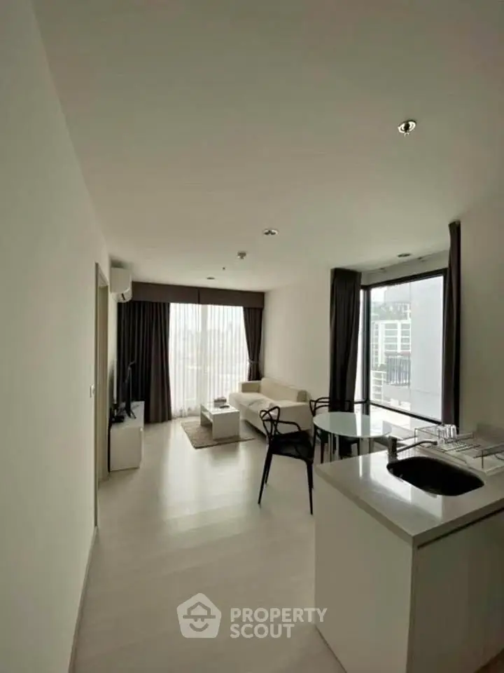 Modern open-plan living room with sleek kitchen and large windows offering city views.