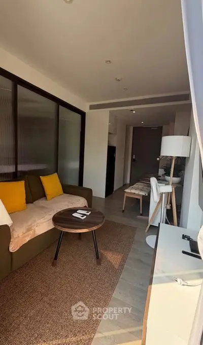 Modern living room with stylish decor and natural light, featuring a cozy sofa and dining area.