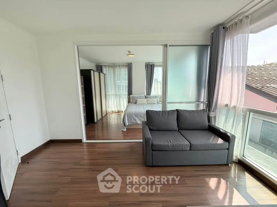 Spacious bedroom with cozy sofa and large windows offering natural light