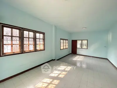 Spacious empty room with large windows and tiled flooring, perfect for customization.