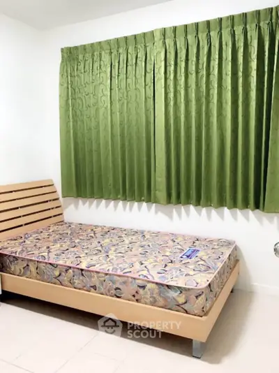 Cozy bedroom with wooden bed frame and vibrant green curtains, perfect for a restful retreat.