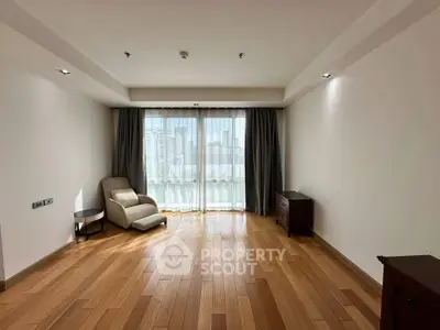 Spacious living room with wooden flooring and large window for natural light.