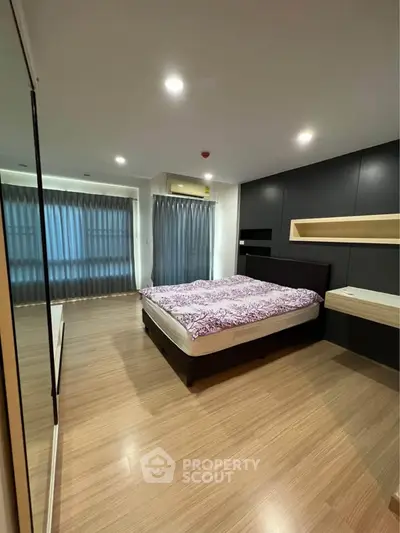 Spacious modern bedroom with elegant wooden flooring and stylish black accent wall.