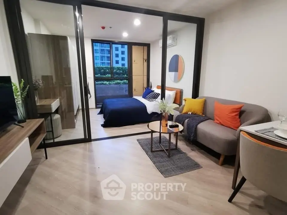 Modern studio apartment with stylish decor and open layout, featuring a cozy living area and bedroom with balcony view.