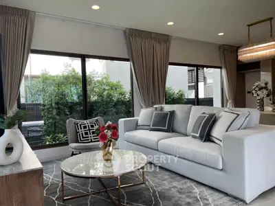 Elegant living room with modern decor and large windows overlooking greenery.
