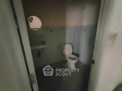 Dimly lit bathroom with toilet and sink, basic design.