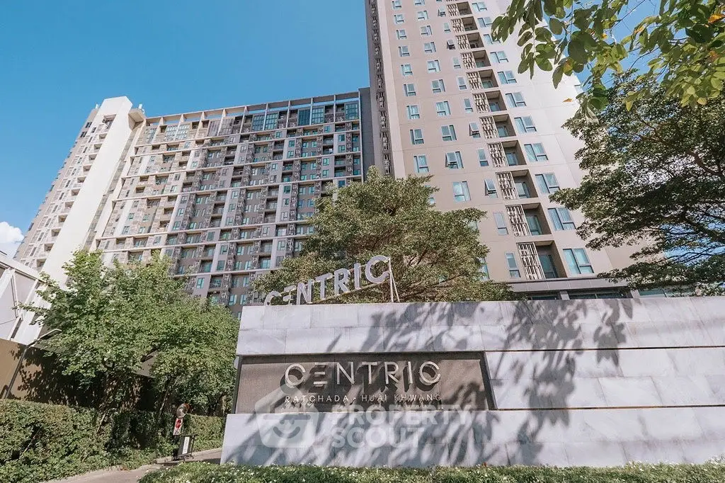 Modern high-rise condominium with lush greenery and stylish entrance signage.