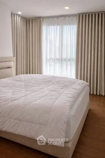 Spacious bedroom with elegant curtains and cozy bed in modern apartment.