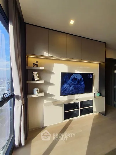 Modern living room with sleek TV unit and large window offering city views.