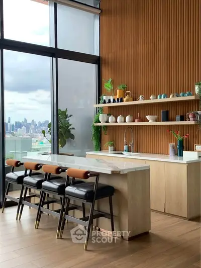 Luxurious modern kitchen with open layout and stunning city view, featuring sleek countertops and stylish bar seating.