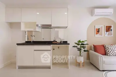 Modern kitchen with sleek cabinetry and cozy living area in stylish apartment.