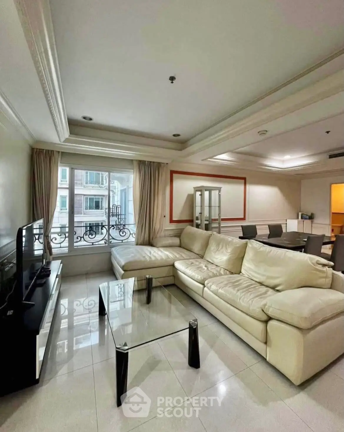 Spacious living room with elegant cream sofa and glass coffee table, perfect for relaxation.