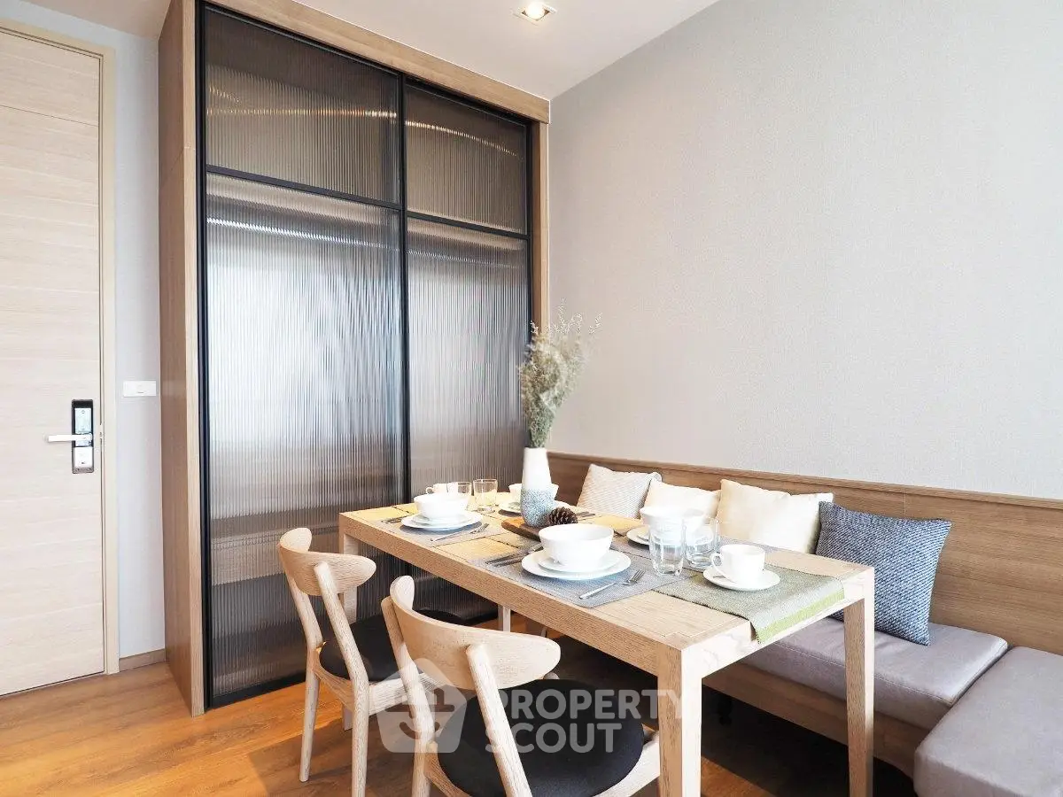 Modern dining area with wooden table and chairs, cozy seating, and elegant decor in a stylish apartment.