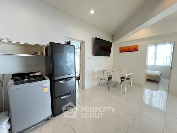 Modern apartment interior with kitchen and dining area, featuring sleek appliances and bright natural lighting.