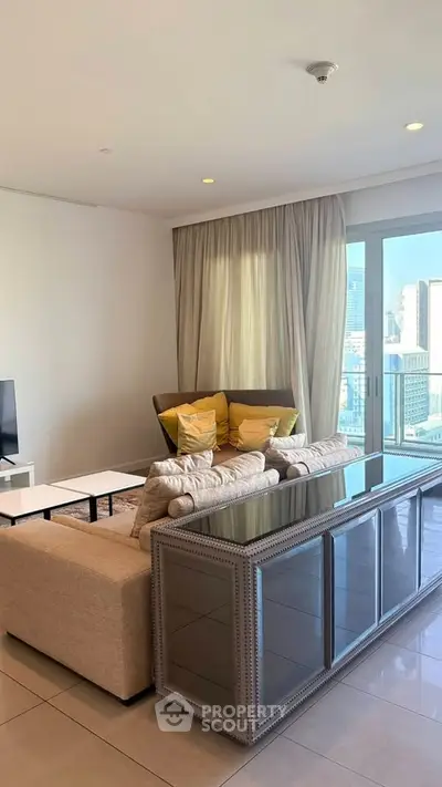 Spacious living room with modern decor and city view, featuring a cozy sofa and elegant furnishings.